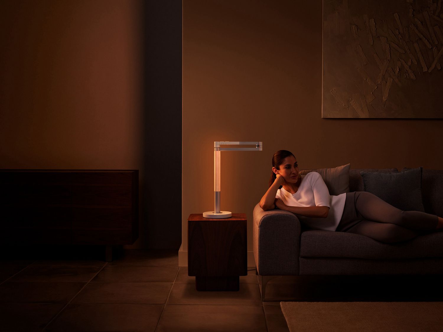 Une femme boit du thé au lit, sous un éclairage relaxant.